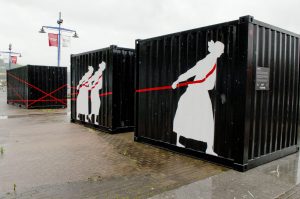 Black containers with white silhouettes of towrope women at Bilbao Maritime Museum